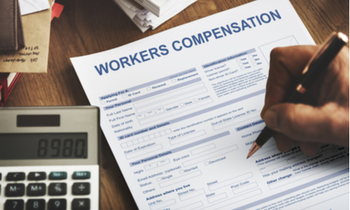 This is an image of a hand filling out a form for workers' compensation benefits in Atlanta