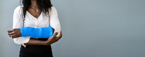 Image of a female employee with injured arm concept of compensable work injuries in Athens