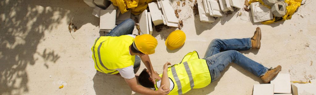A worker is unconscious on the ground after a workplace accident.